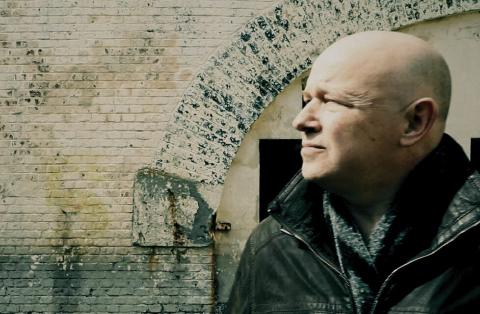 Imprisoned Pastor in Sudan Preaches to 300 Inmates A man stands in front of a building looking away from the camera