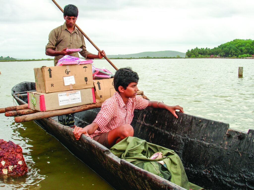 two boys carrying supplies in their canoe