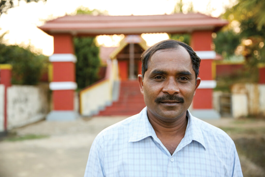 man stands facing the camera and smiling